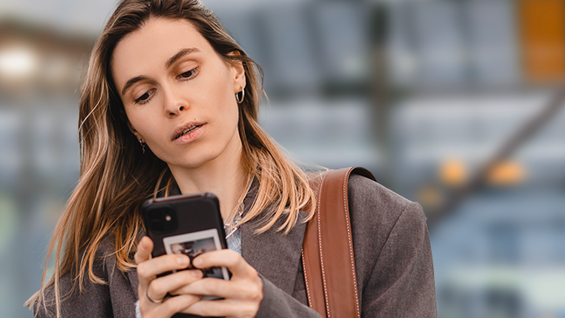 Woman looking at the phone at a bus station