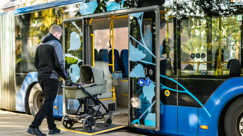 A treveller with a pram getting on a bus through a ramp