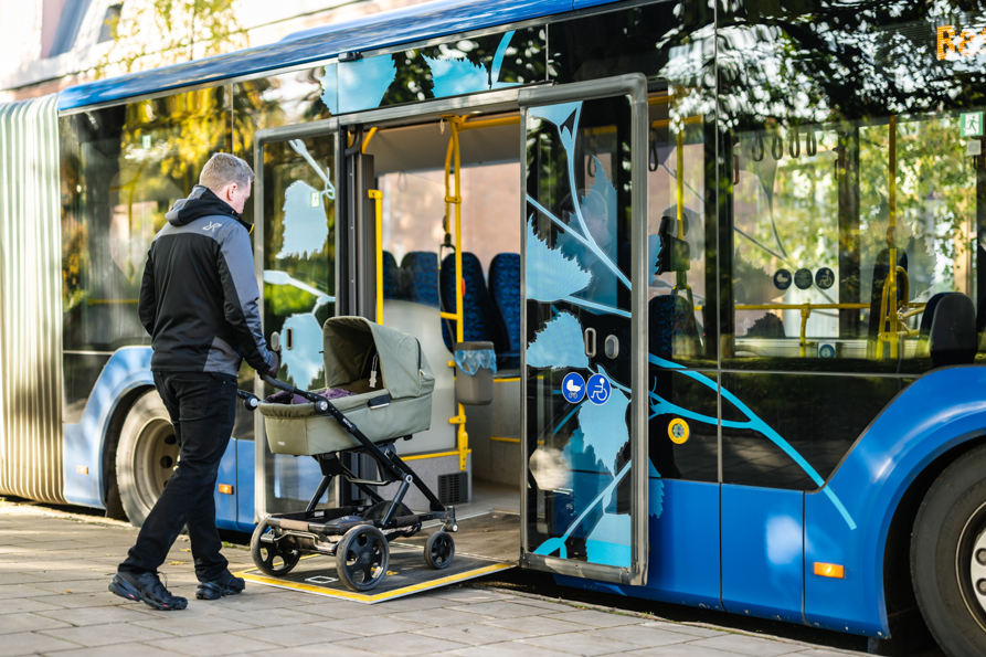 En resenär med barnvagn kliver ombord på bussen med hjälp av en ramp