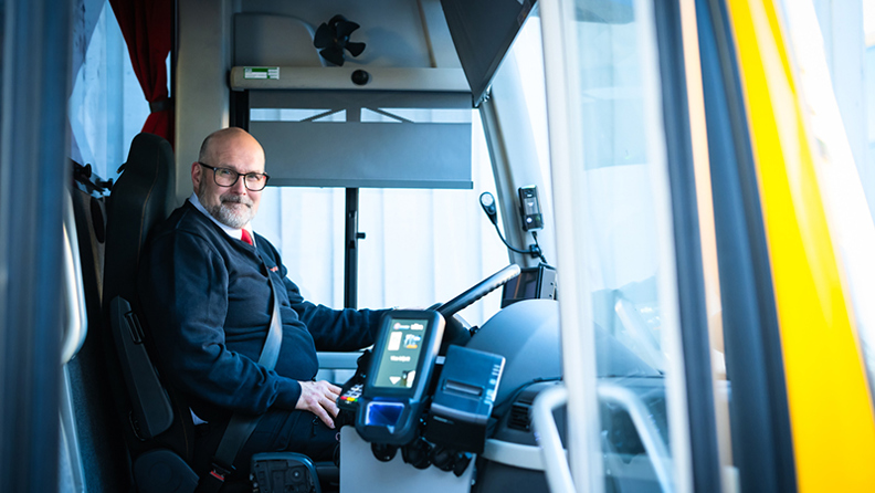 Bussförare Nisse bakom ratten i sin buss