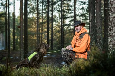 Bussförare Göran bär jaktkläder och är i skogen med sin hund