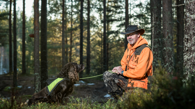 Bussförare Göran bär jaktkläder och är i skogen med sin hund